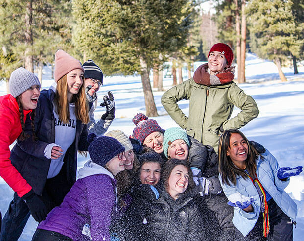 Smiling group of students in winter parkas outside posing and having fun