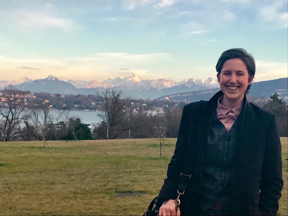 Mary Beall standing in a field with mountains in the background