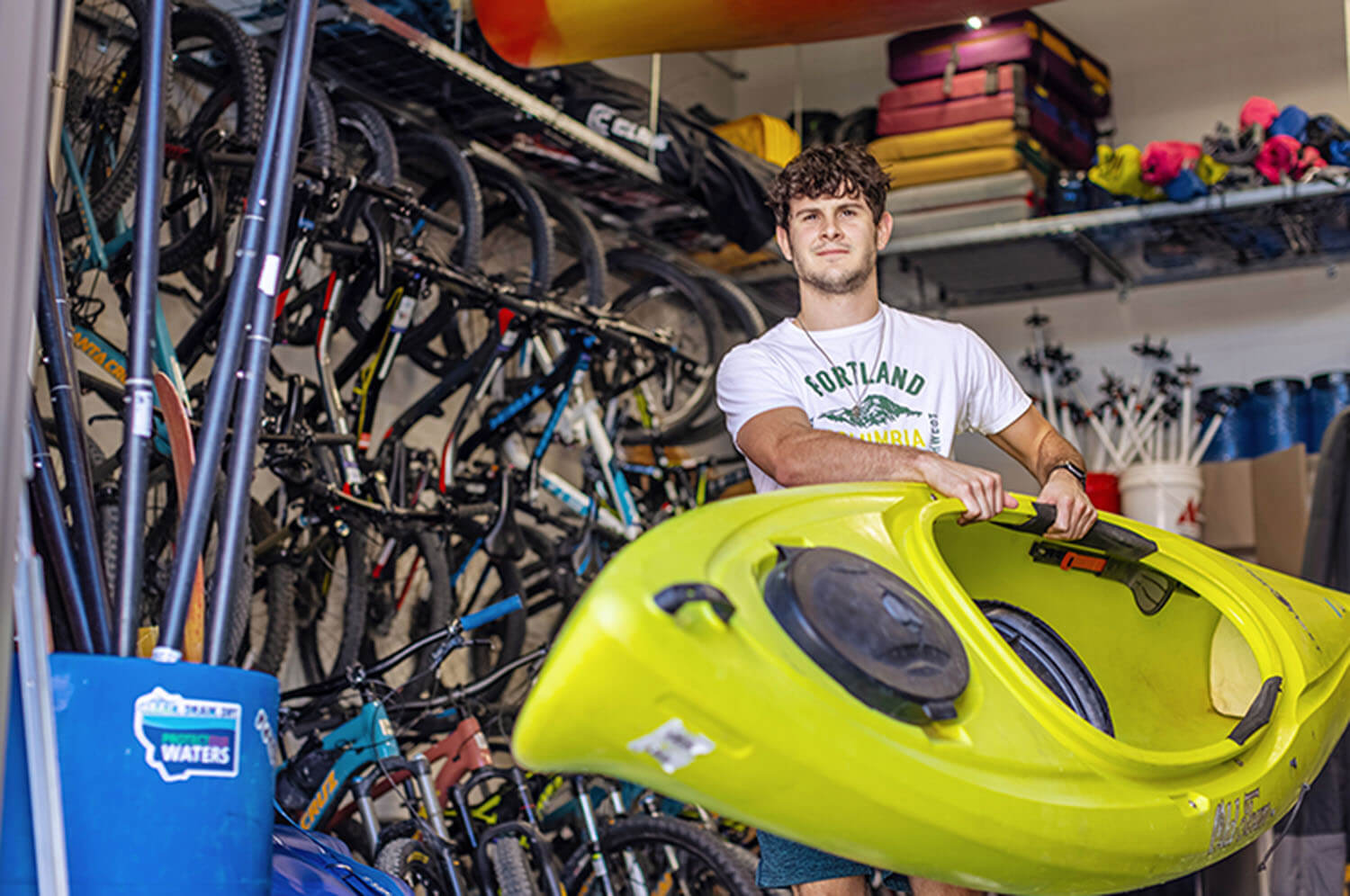 Student carries a bright kayak out of the storage facility