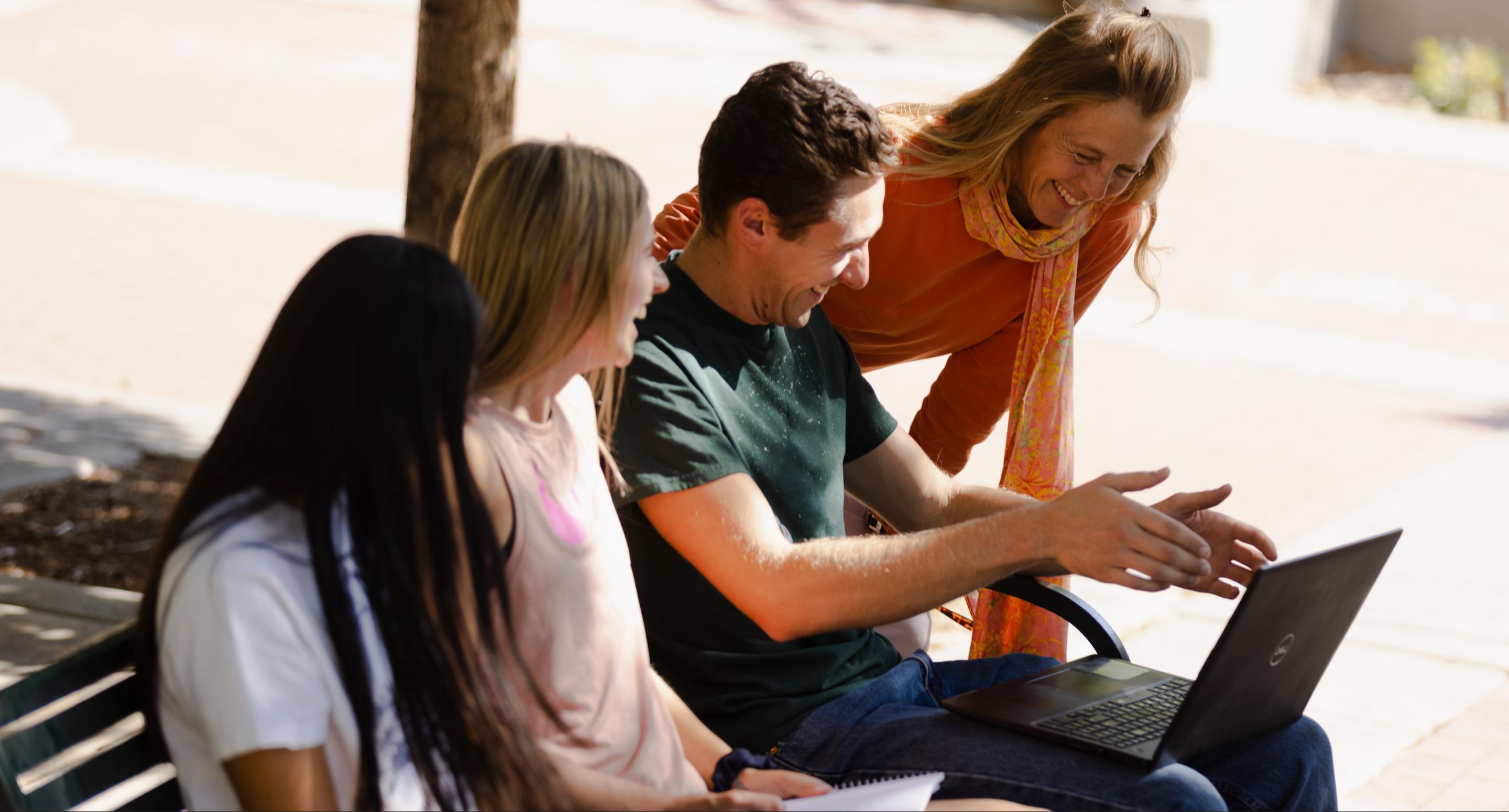 Students outside on bench with professor